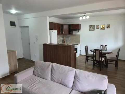 Living room with a sofa, dining area, and kitchen in the background. - image 3