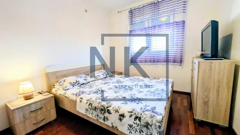 Furnished bedroom with a double bed, bedside tables, and a TV.
