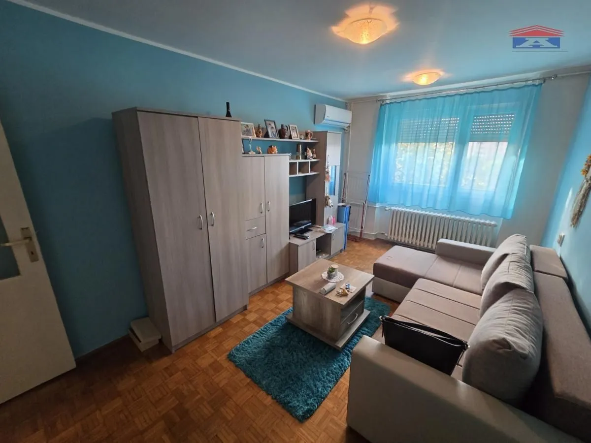 Dnevna soba sa garniturom za sedenje, garderoberom i televizorom.
