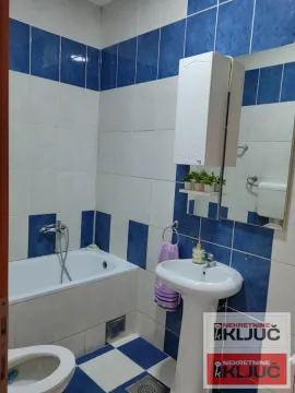 Kupatilo opremljeno kadom, umivaonikom, ogledalom i pločicama u plavo-belim tonovima. - image 5