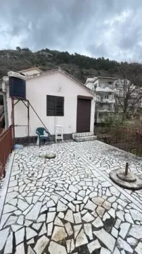 Pogled na dvorište i spoljašnjost kuće sa popločanom terasom. - image 2