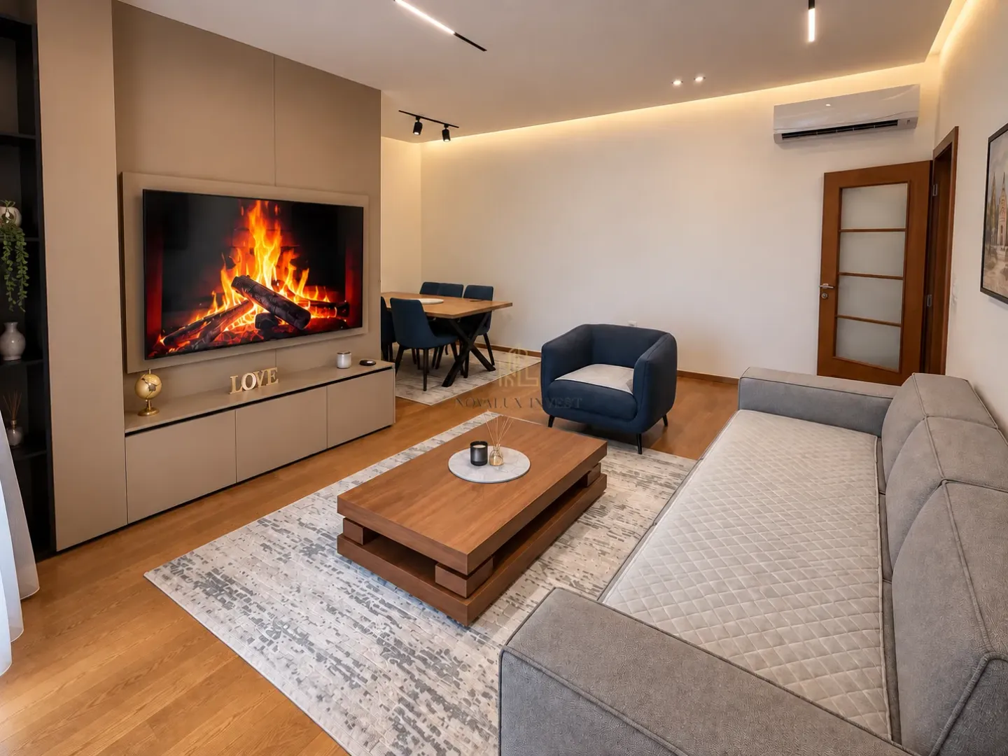Modern living room with a sofa, TV, and dining area in the background.