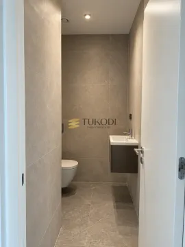 Manje kupatilo obloženo sivim pločicama sa toaletom i umivaonikom. - image 7