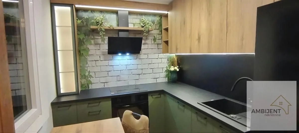 Modern kitchen with dark countertops, wooden cabinets, and a brick-pattern wall.