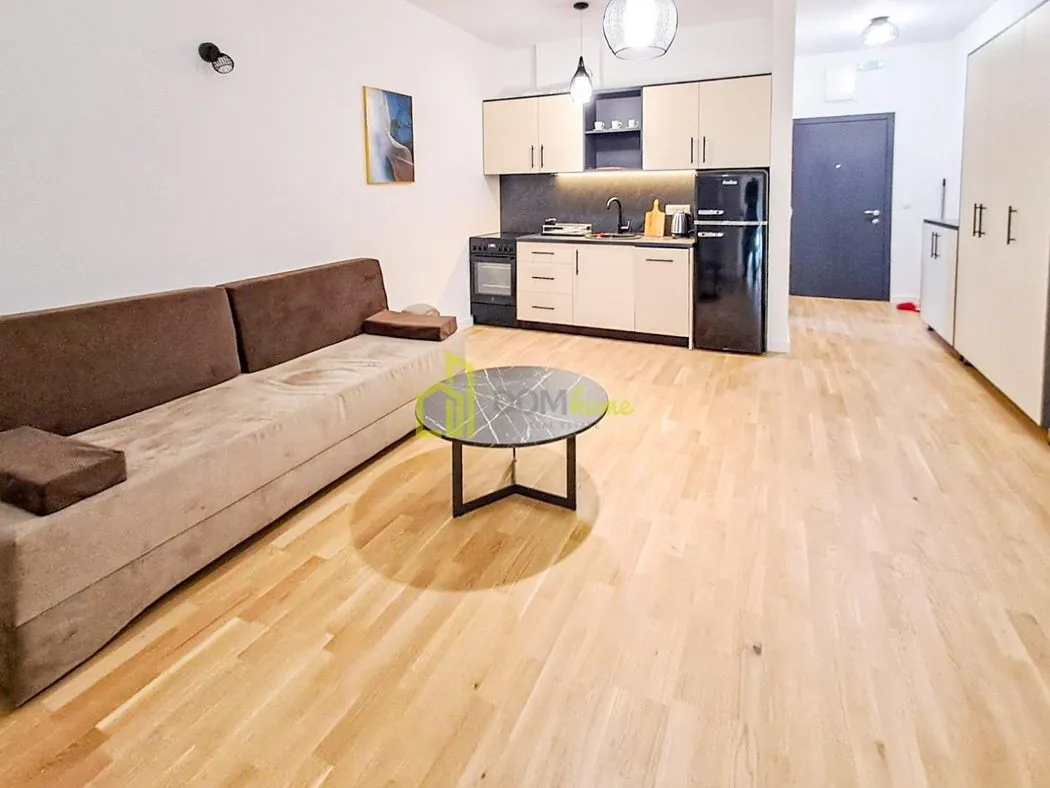 Living room with a sofa and a kitchen in the background.