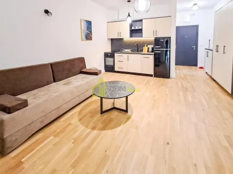 Living room with a sofa and a kitchen in the background. - image 8