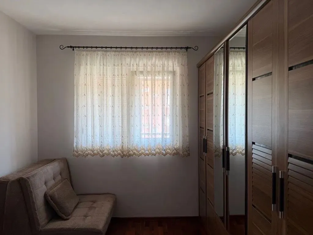 Small bedroom with a sofa, window, and built-in wardrobe.