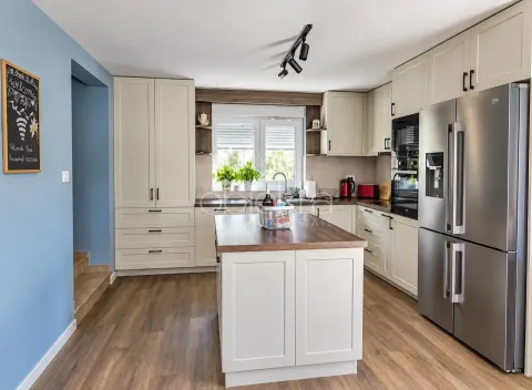 Modern kitchen with an island, light-colored cabinetry, and a large refrigerator. - image 10