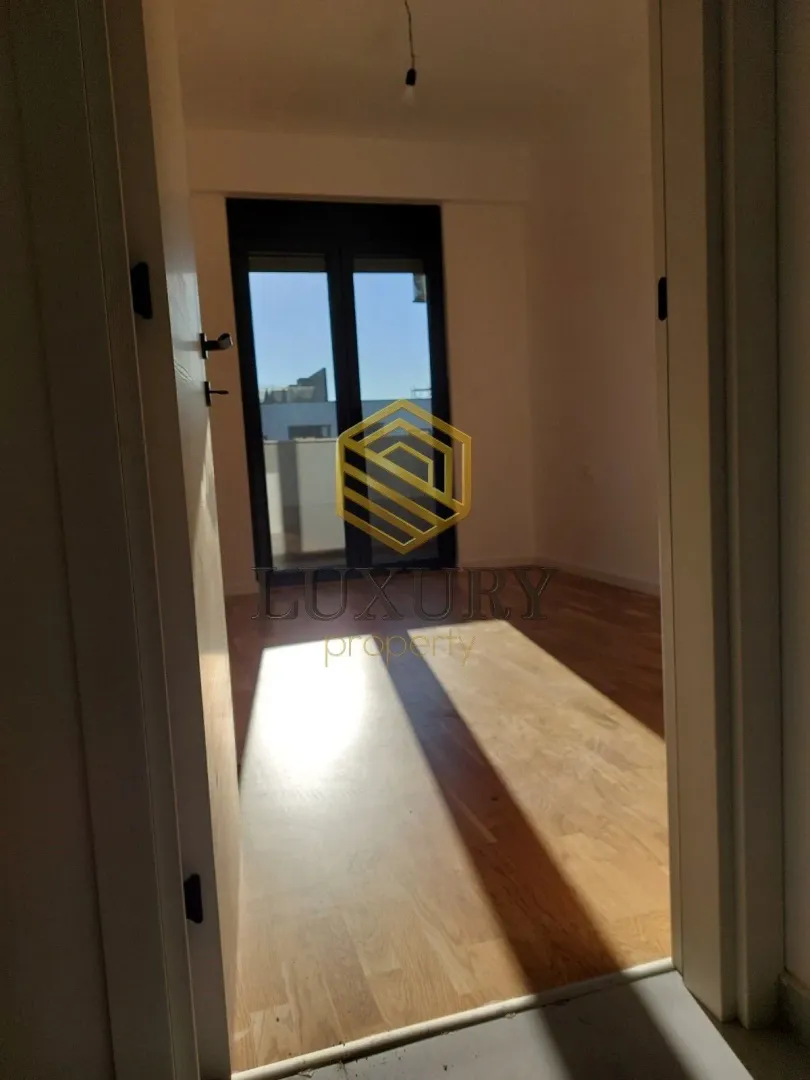 View through the doorway into an empty room with wooden flooring.