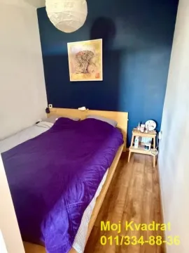 Nameštena spavaća soba sa bračnim krevetom i tamnoplavim zidom. - image 4