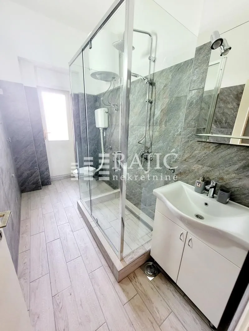 Modernly equipped bathroom with a walk-in shower and vanity unit.
