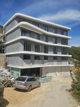 Exterior view of a multi-story residential building under construction with surrounding area and a car parked in the yard. - image 11