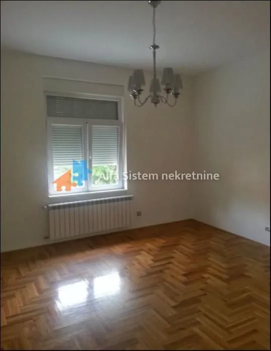 Empty room with parquet flooring and a chandelier.