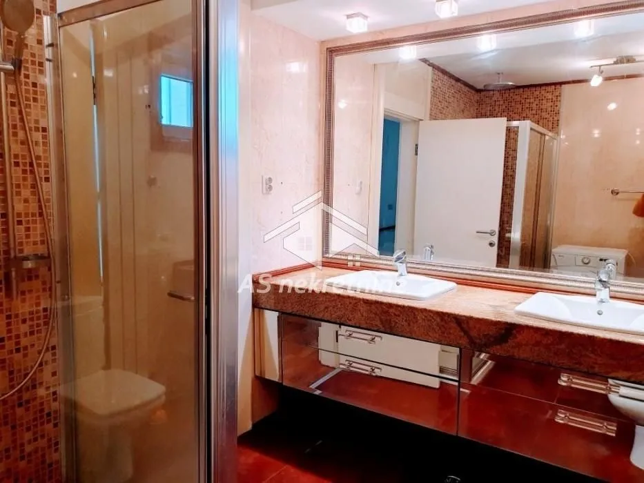 Bathroom with double washbasin, large mirror and shower cabin.