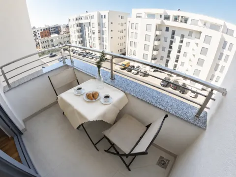 Namješten balkon sa stolom, stolicama i pogledom na naselje. - image 9