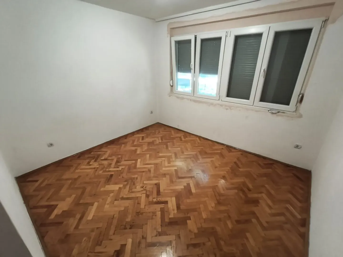 Empty room with parquet flooring and white walls.