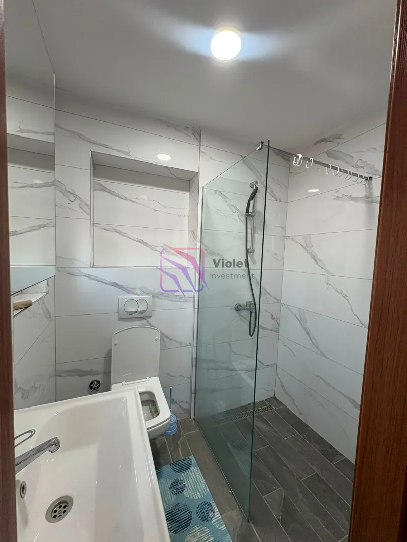 Modernly equipped bathroom with a walk-in shower and marble-effect tiles.