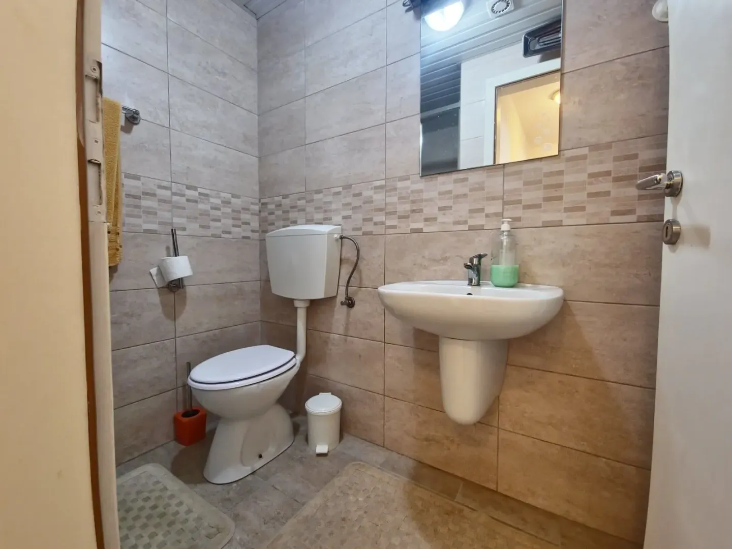 Smaller bathroom with a toilet, washbasin, and mirror.