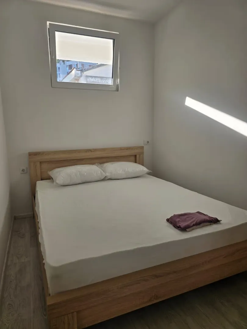 Spavaća soba sa bračnim krevetom i prozorom na zidu.
