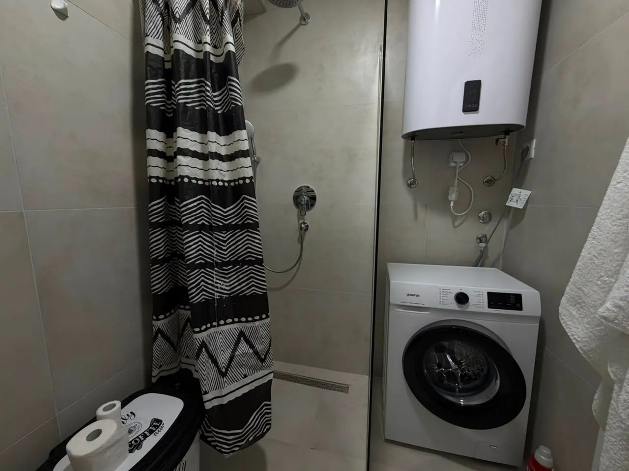 Bathroom with a shower cabin, water heater, and washing machine.