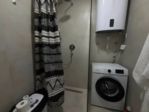 Bathroom with a shower cabin, water heater, and washing machine. - image 4