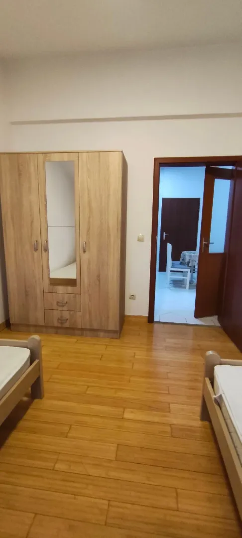 Furnished bedroom with wooden flooring, a wardrobe, and beds.