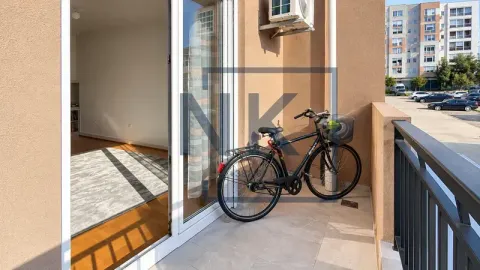 Balkon sa biciklom i pogledom na parking i zgrade. - image 9