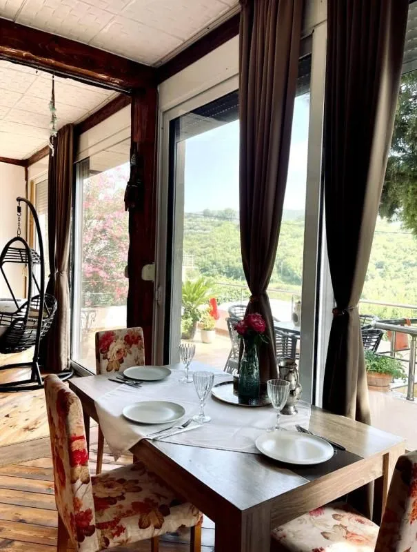 Dining area with a dining table and large windows overlooking nature.