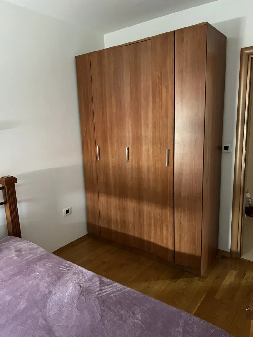 A large wooden wardrobe next to a bed in a bedroom.