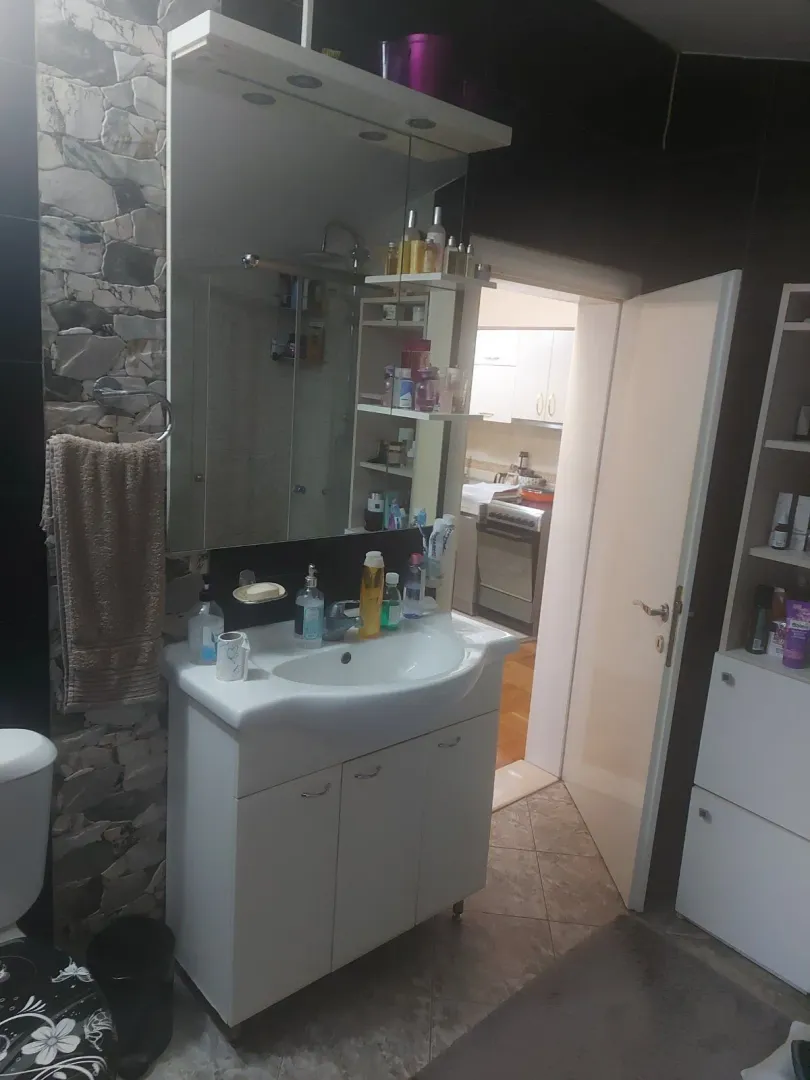 Kupatilo sa bijelim lavaboom i ogledalom.
