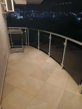 Prostrana popločana terasa sa metalnom ogradom i pogledom na grad noću. - image 6