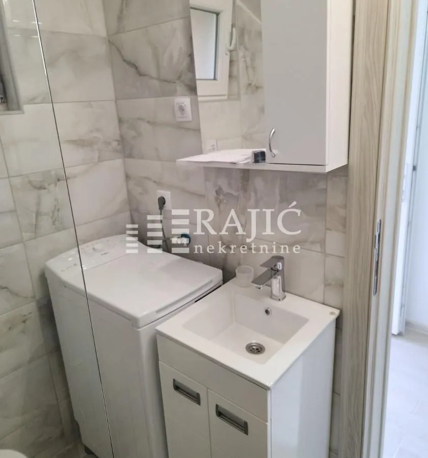 Smaller bathroom with a sink, cabinet, and washing machine.