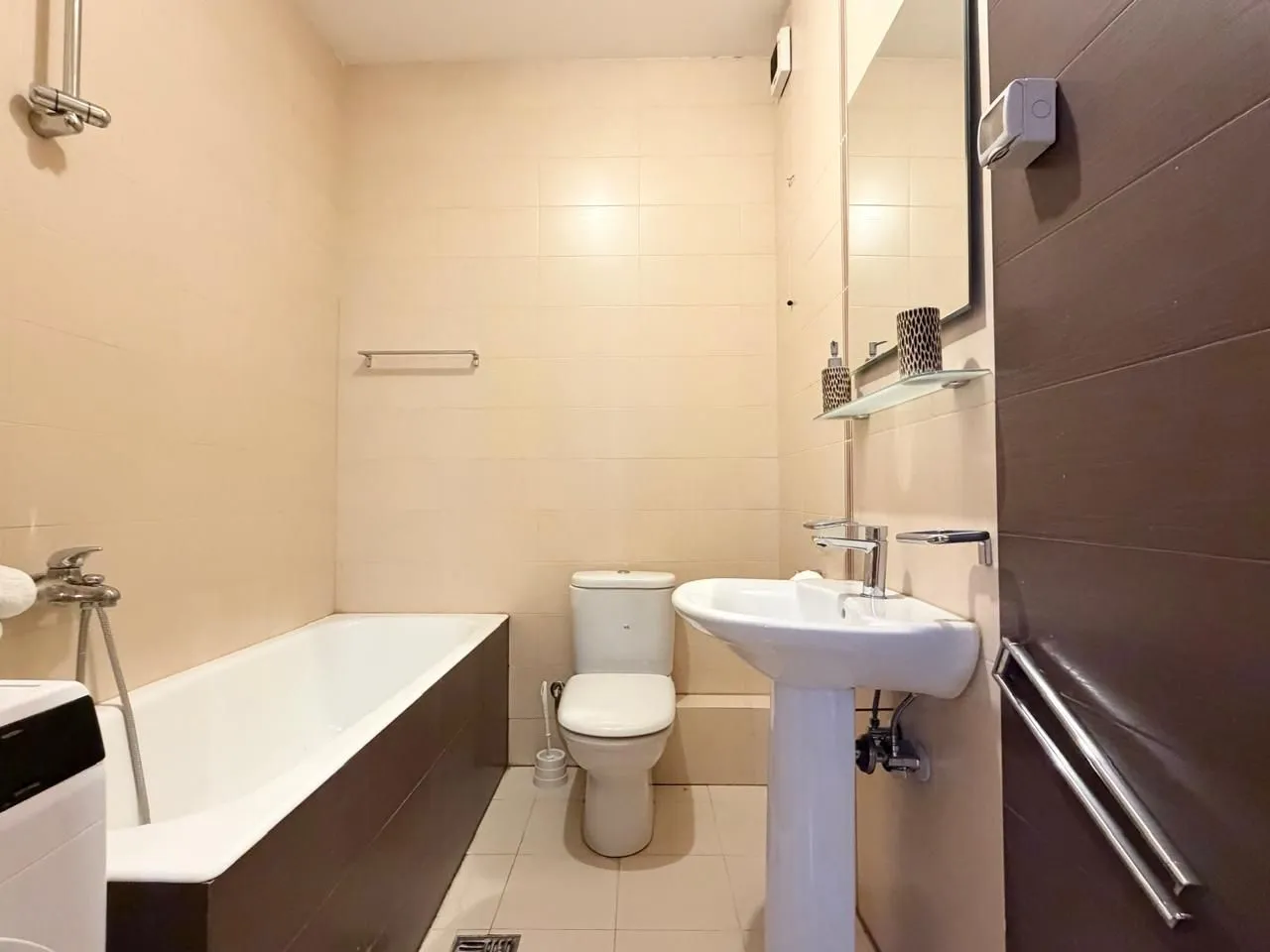 Manje kupatilo sa kadom, umivaonikom i toaletnom šoljom.