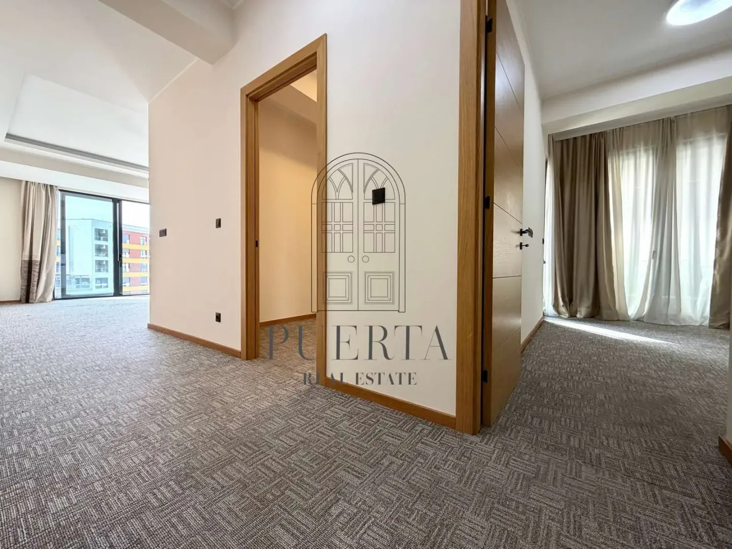 Spacious bright carpeted living room with interior wooden doors.