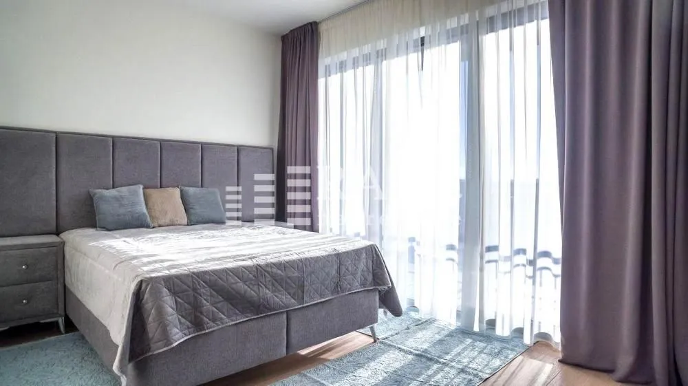 Bright bedroom with a double bed and large balcony doors.