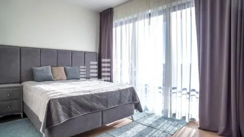 Bright bedroom with a double bed and large balcony doors. - image 6