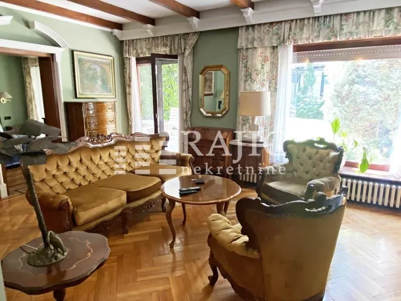 Living room with classical furniture, wooden flooring, and a large window.