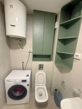 Smaller bathroom with a toilet, washing machine, water heater and green cabinet. - image 7