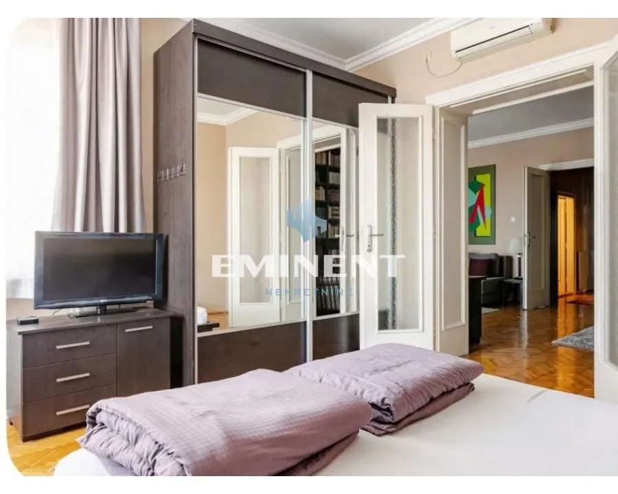 Furnished bedroom with a large wardrobe, bed, and television.