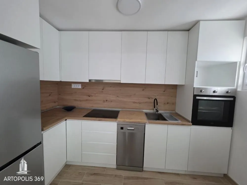 Modern kitchen with white units and wooden worktops.