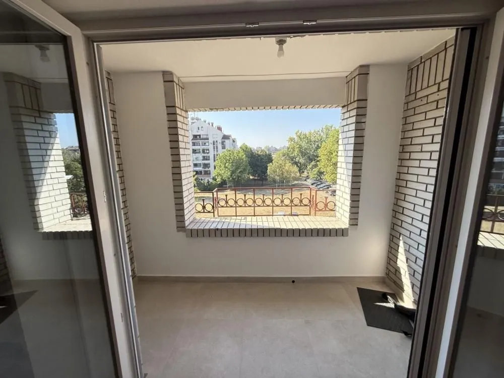 Covered balcony with a view of the park and surrounding buildings.