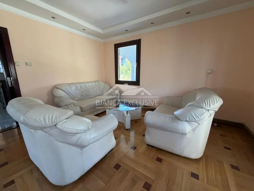Dnevna soba sa garniturom za sedenje i drvenim podom.