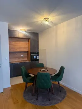 Modern kitchen with a dining table and green chairs. - image 2