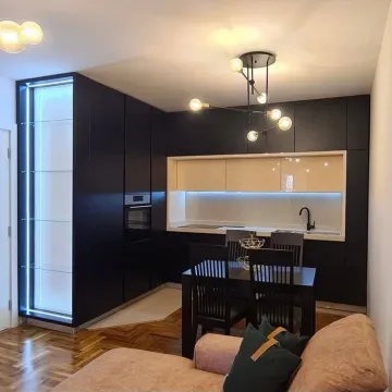 Moderna kuhinja sa tamnim elementima i trpezarijskim stolom. - image 4