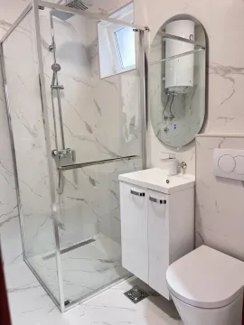 Savremeno opremljeno kupatilo sa tuš kabinom, umivaonikom i wc šoljom. - image 6