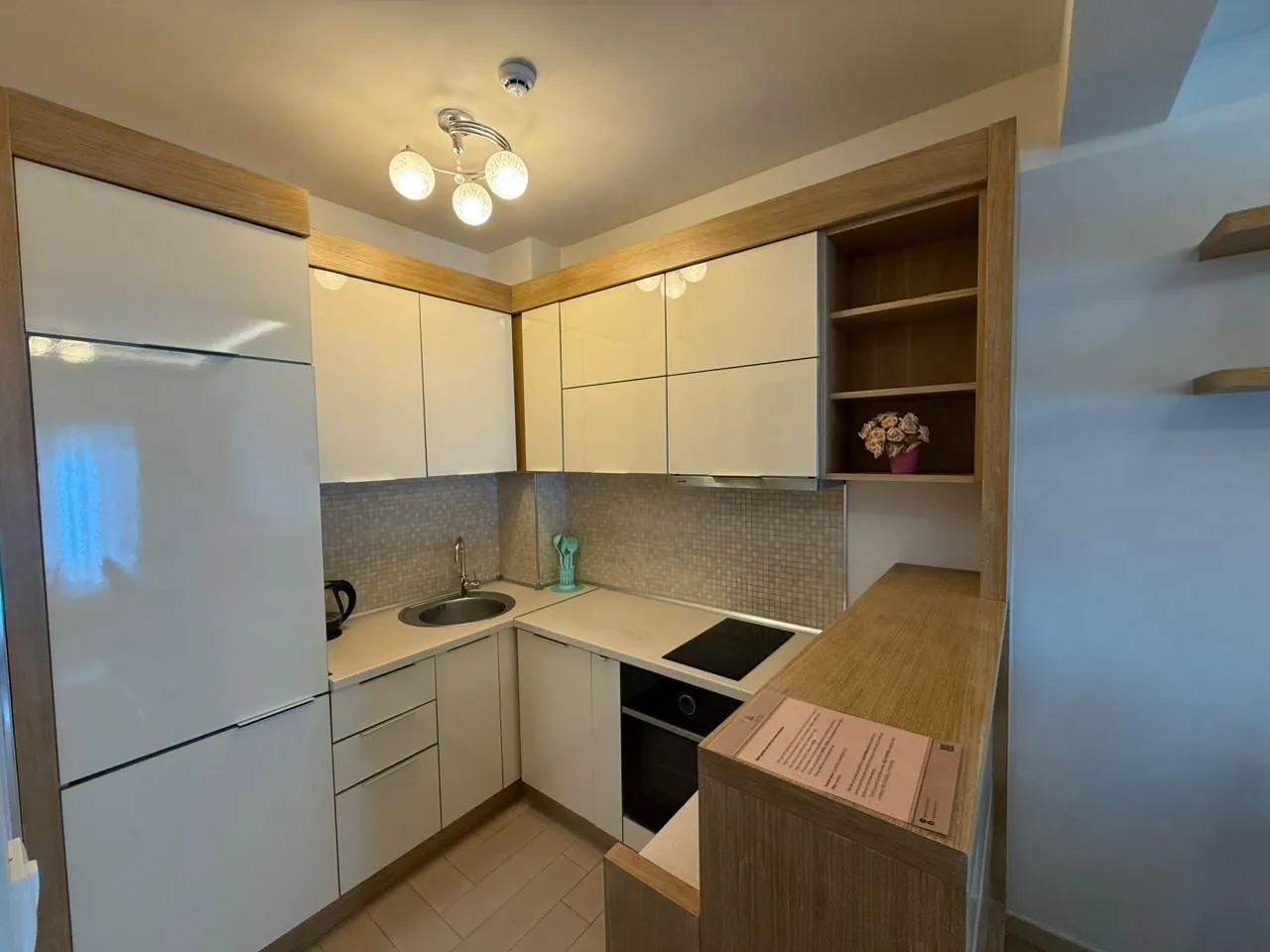 Small equipped kitchen with white units and wooden details.