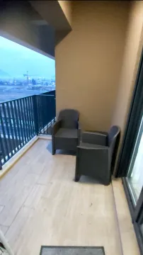 Covered balcony with two armchairs and a city view. - image 8