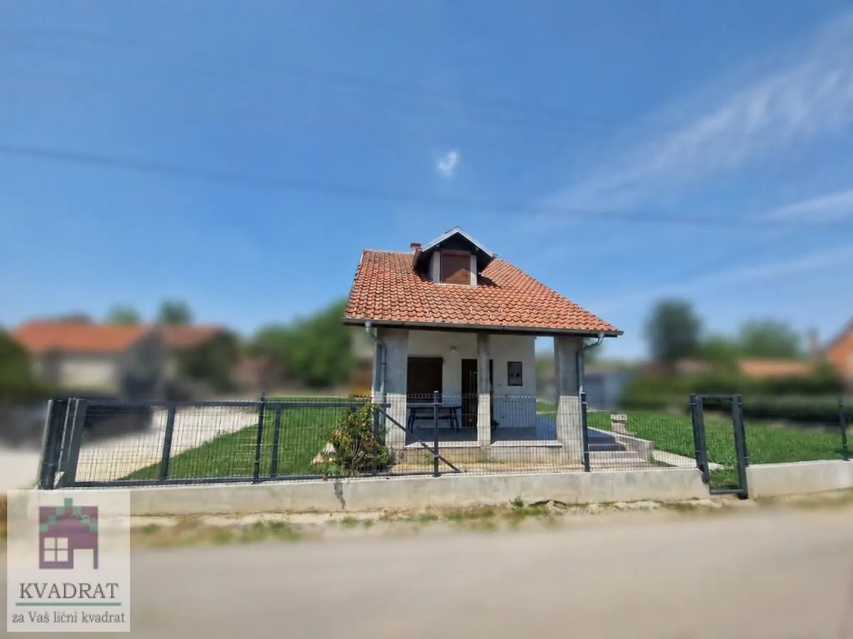 Pogled na manju kuću sa dvorištem i ogradom.