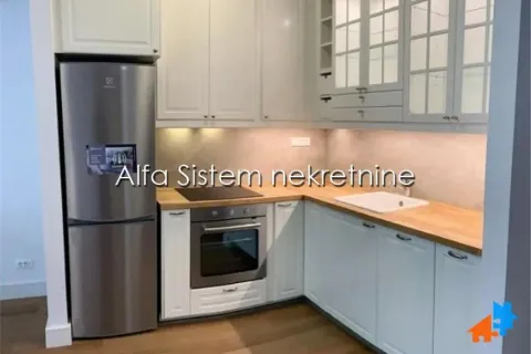 Kuhinja opremljena belim elementima, drvenom radnom pločom i frižiderom. - image 7