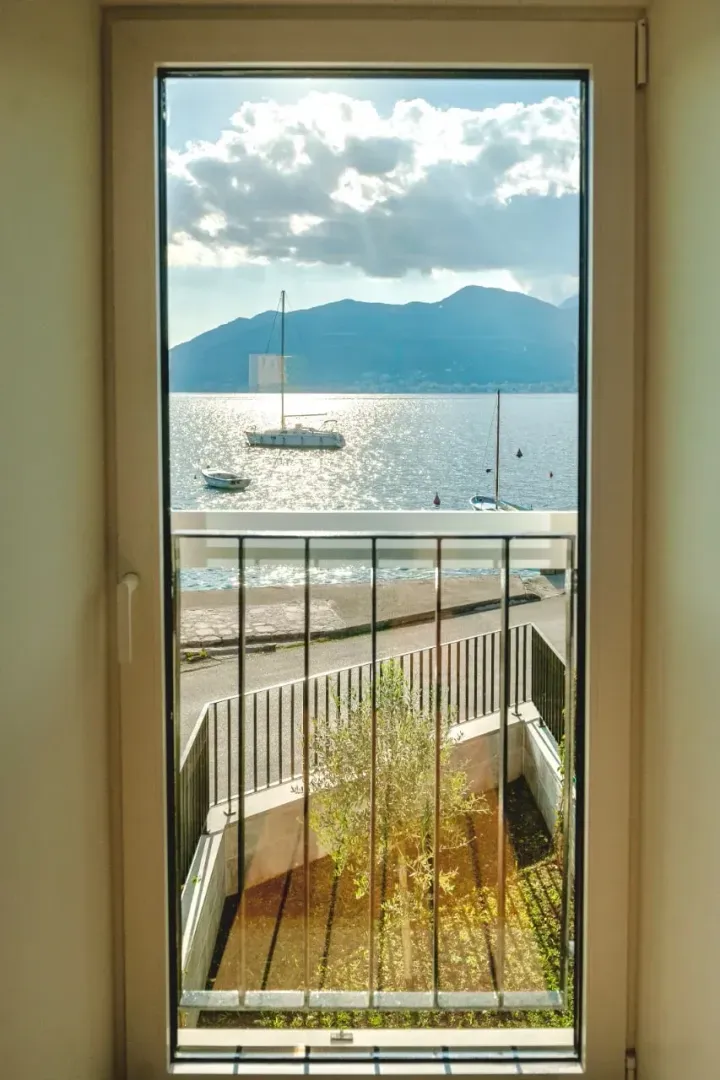Pogled sa prozora na more, planine i sidrište sa brodićima.